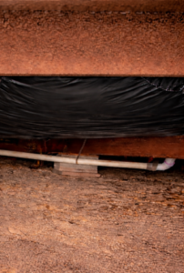 mobile home underbelly repair with new black vapor barrier installed beneath manufactured home crawlspace.